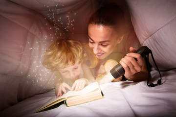 Pretty woman and her son reading a book at night