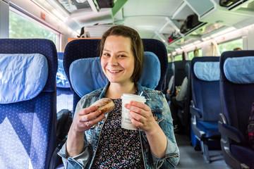 Girl in the train drinking coffee and eating donut