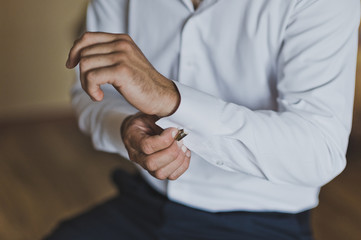 Fototapeta premium Young man buttoning the cuff links on the sleeves 7441.