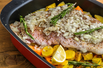 Raw lamb shank with roots and onion ready for frying on a rustic wooden board. Close view