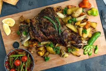 Roast shoulder of lamb on baked potato and carrots, wooden board, top view - 135499027