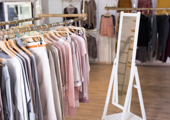 Fototapeta na wymiar Knitted clothing on hangers in garment store