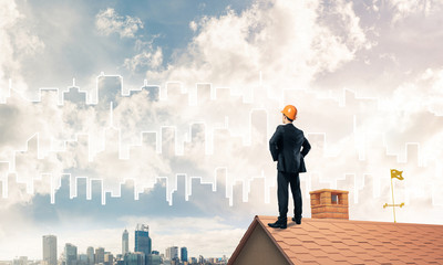 Engineer man standing on roof and looking away. Mixed media