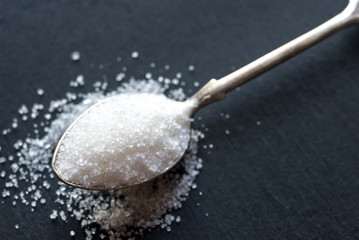 Spoon with white sugar on the dark background