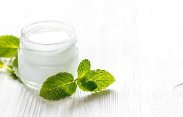 organic cosmetics with herbal extracts of mint on wooden background