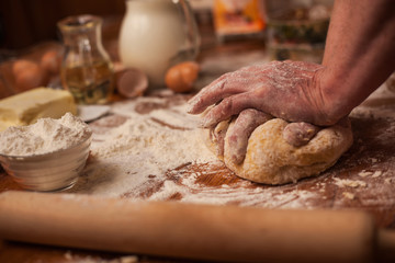 Fototapeta na wymiar Senior woman hands knead dough on table in home kitchen