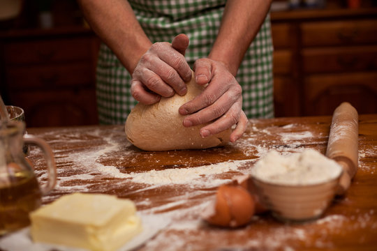 Senior man hands knead dough on table ,home kitchen