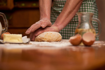 Obraz na płótnie Canvas man hands knead dough on a table in her home kitchen