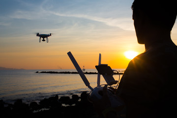 Man operating of flying drone quadrocopter at sunset