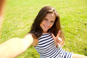 young happy woman on grass taking selfie