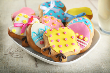 Plate with colourful Easter cookies on kitchen table, closeup
