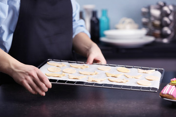 Woman holding baking grid with raw Easter cookies, closeup