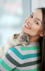 Beautiful young woman with cute cat at home