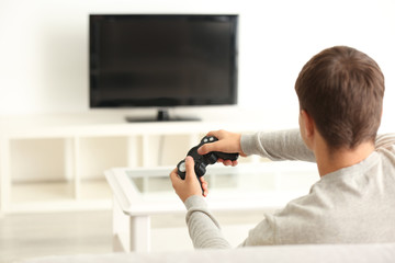 Teenager playing videogame at home