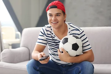 Tuinposter Teenager watching football match at home © Africa Studio