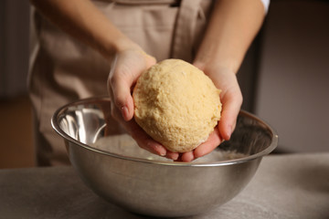 Young woman making dough in kitchen, closeup
