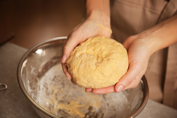 Young woman making dough in kitchen, closeup