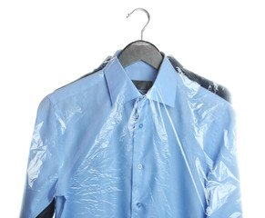 Clean clothes from dry-cleaning on white background