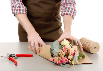 Obraz na płótnie Canvas Male florist wrapping flower bouquet in paper on white background