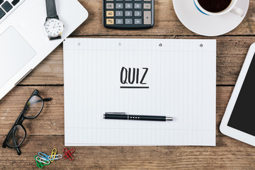 Quiz text on note pad, Office desk with computer technology, hig