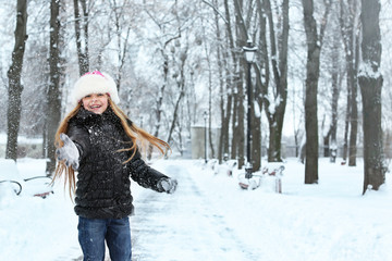Cute little girl playing with snow in winter park