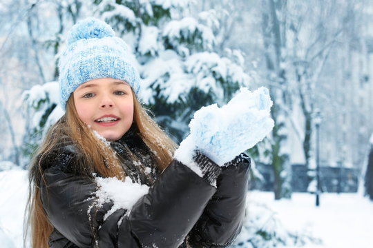 Cute little girl playing with snow in winter park