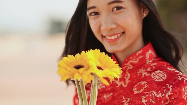 Beautiful Vietnamese girl in red traditional dress Ao Dai with yellow flowers. Close-up.