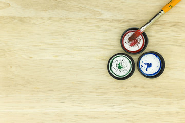 Three bottle cap with a painting brush on the top right side of the wooden background