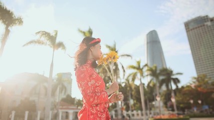 Girl in traditional Vietnamese dress spinning happy with yellow flowers. The mood of delight. Vietnam.