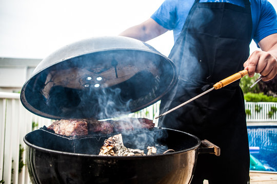 Grillmaster Flipping Mea On A Smoking Grill