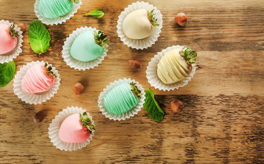 Strawberries covered with colorful chocolate icing on wooden background