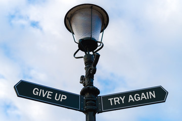 Give Up versus Try Again directional signs on guidepost