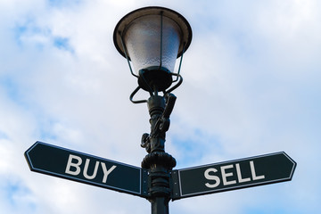 Fototapeta na wymiar Buy versus Sell directional signs on guidepost