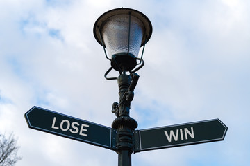 Lose versus Win directional signs on guidepost