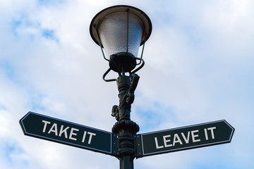 Fototapeta na wymiar Take It versus Leave It directional signs on guidepost