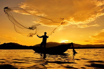 Silhouette of fisherman throwing fishing net in Thailand