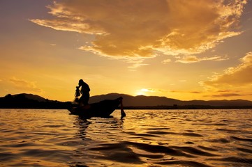 Silhouette of fisherman throwing fishing net in Thailand