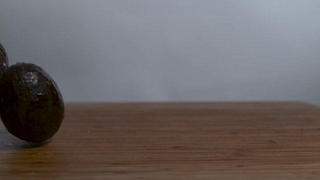 Avocados rolling in slow motion onto a cutting board