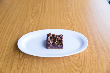 Caramel chocolate chip brownie on white plate on wooden table