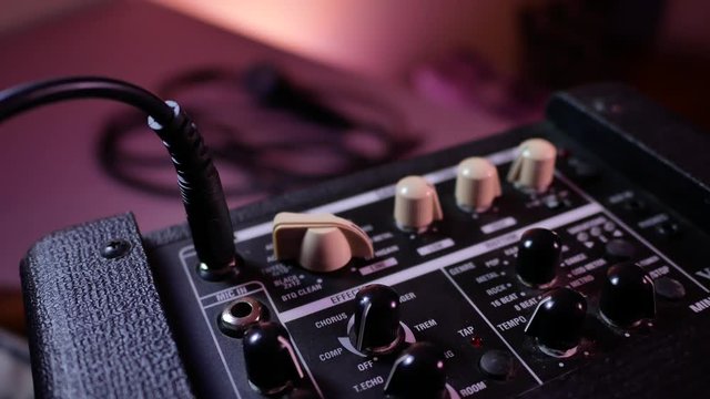Man's hand removes the cable jack from guitar amp