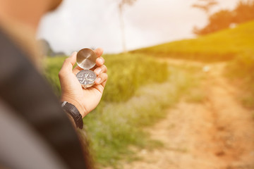 Hand holding a compass on nature background.