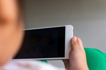 Little girl watching cartoon on mobile device.