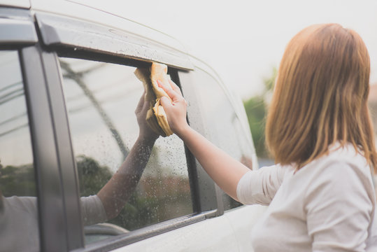 woman washing car window with microfiber cloth