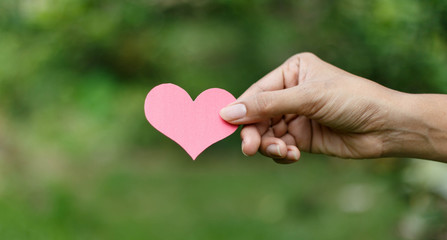 Hands holding heart against nature background