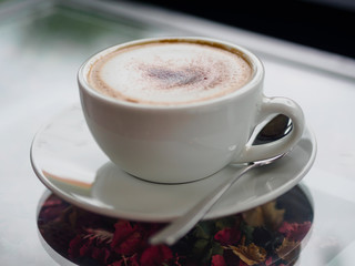 cappuccino coffee on white cut and on glass table with blur background