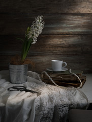 Still life with hyacinth, cup of coffee, old books, scissors on a background of rough wooden walls. vintage.