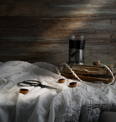 Still life with cup of coffee, old books, scissors on a background of rough wooden walls. vintage