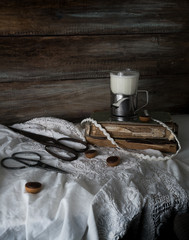 Still life with old books, scissors and a glass of milk on a background of rough wooden walls. vintage