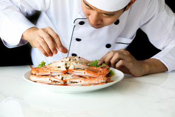 Asian chef preparing and decorating grilled crab seafood meal with vegetable