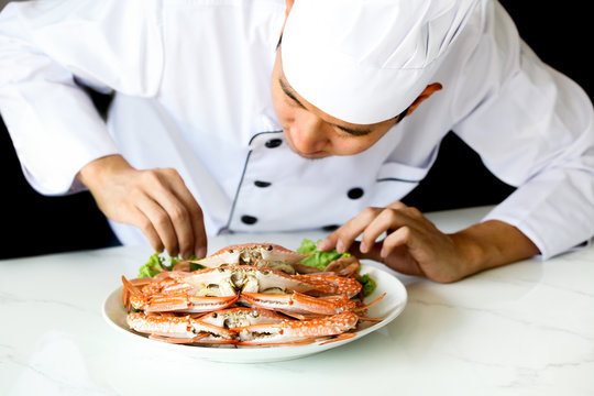 Asian chef preparing and decorating grilled crab seafood meal with vegetable